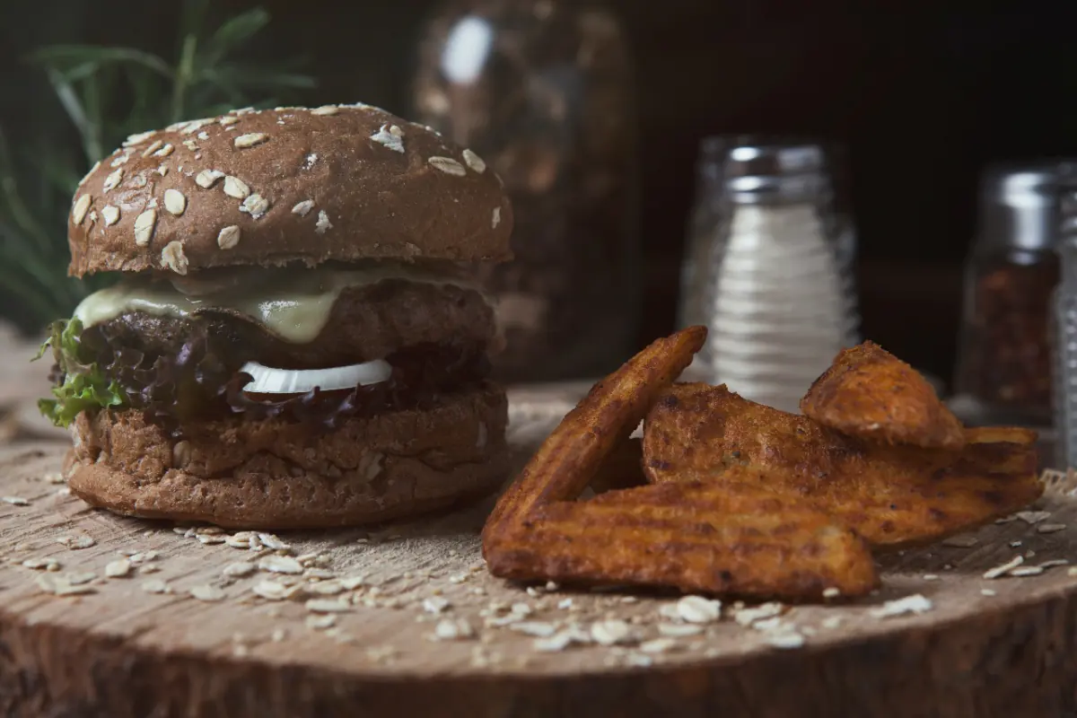 Hamburguesa artesanal con papas en cascos sobre una tabla de madera